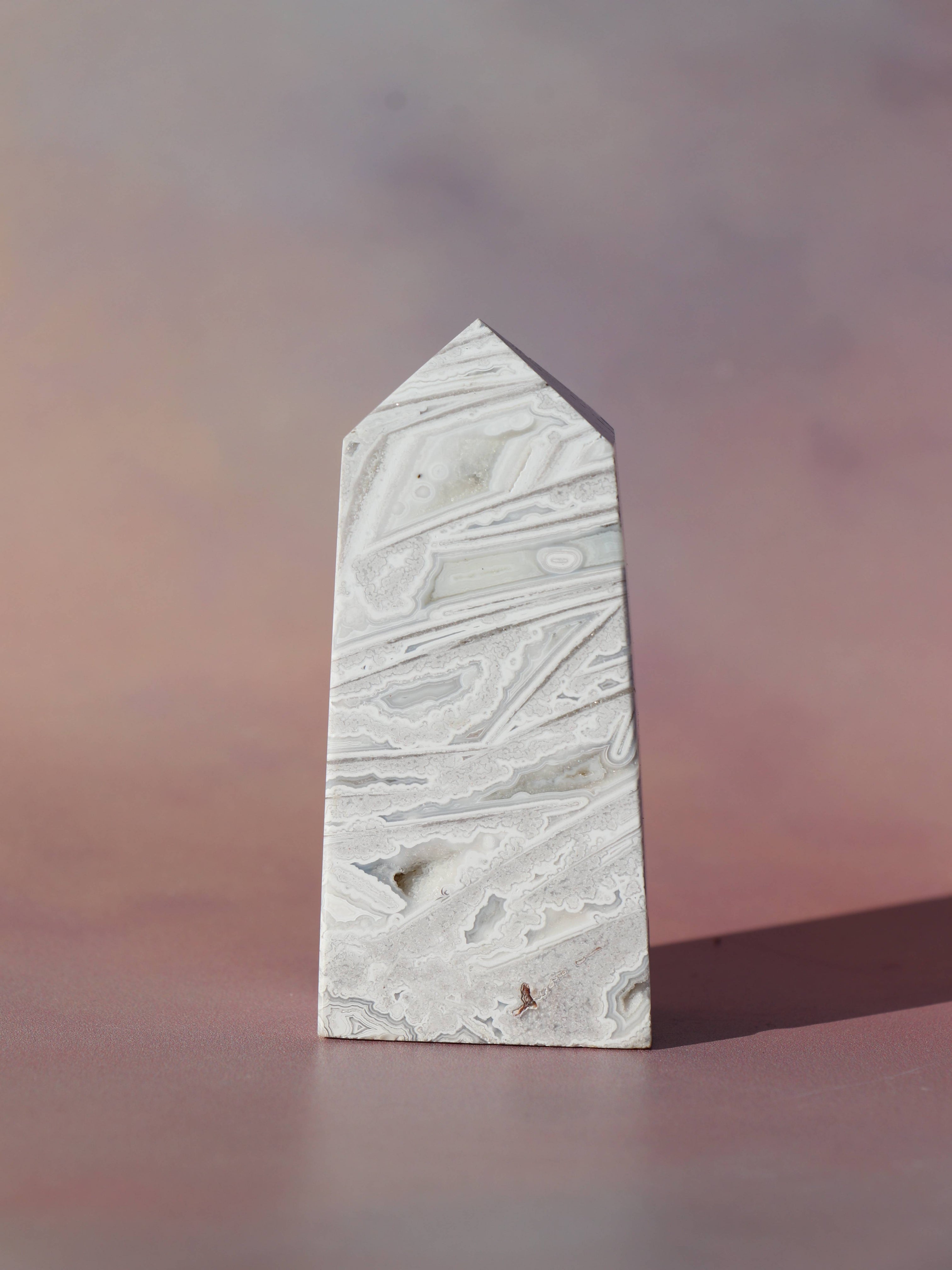 White Lace Agat er en smuk, hvid sten med fine bånd, der bringer ro og klarhed til sindet. Den støtter dig i følelsesmæssig balance, indre fred og selvaccept. Brug den til meditation, stresslindring eller som støtte i svære perioder. En perfekt krystal til dig, der ønsker mere lys og lethed i hverdagen.