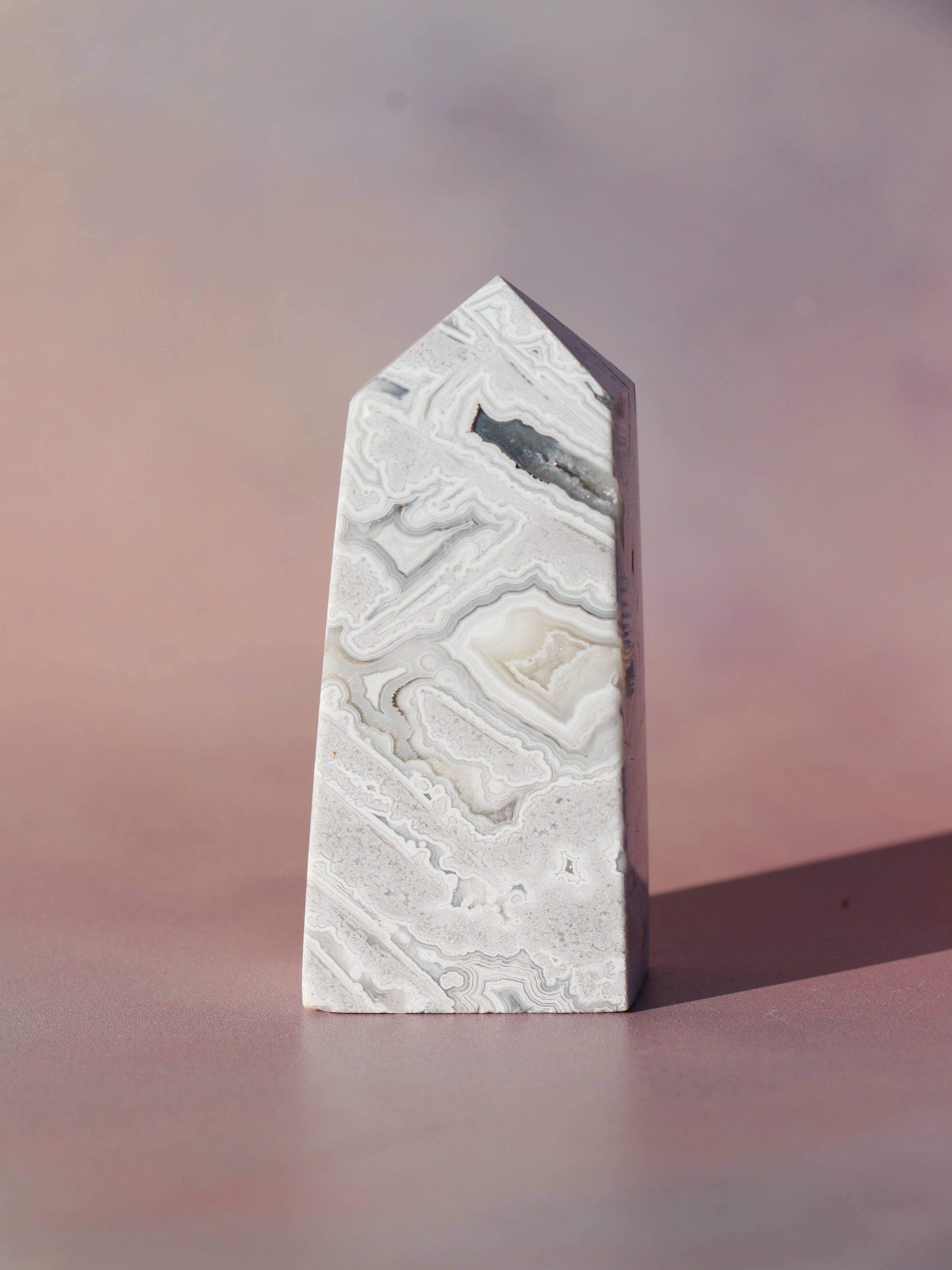 White Lace Agat er en smuk, hvid sten med fine bånd, der bringer ro og klarhed til sindet. Den støtter dig i følelsesmæssig balance, indre fred og selvaccept. Brug den til meditation, stresslindring eller som støtte i svære perioder. En perfekt krystal til dig, der ønsker mere lys og lethed i hverdagen.